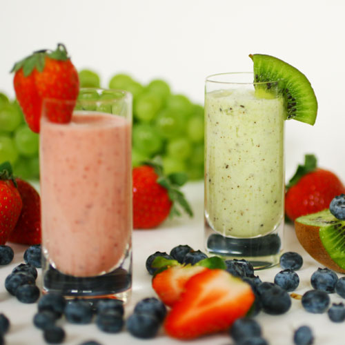 Photo of two fruit smoothies in glasses with garnish.